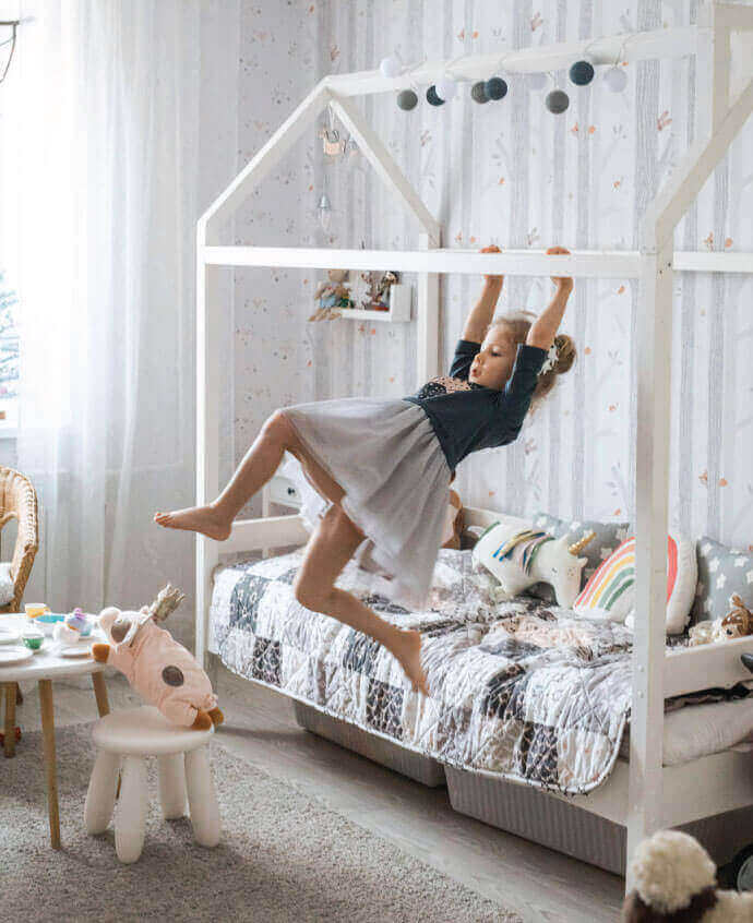 A Little Girl Jumping In The Air On A Bed