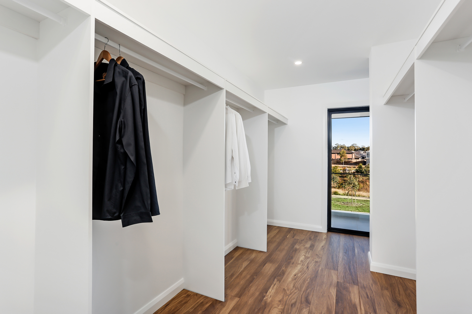 A Walk In Closet With A Wooden Floor And White Walls