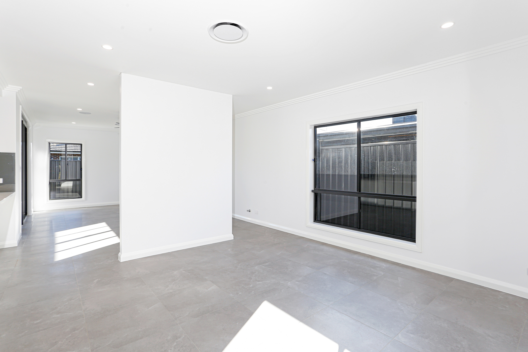 An Empty Room With A Large Window And White Walls