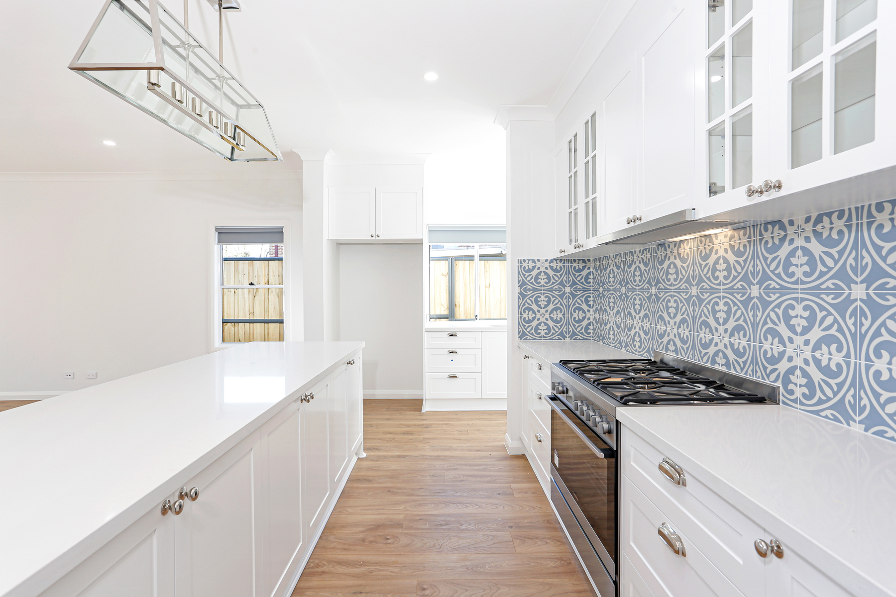 A Kitchen With White Cabinets And A Blue Tile Backsplash
