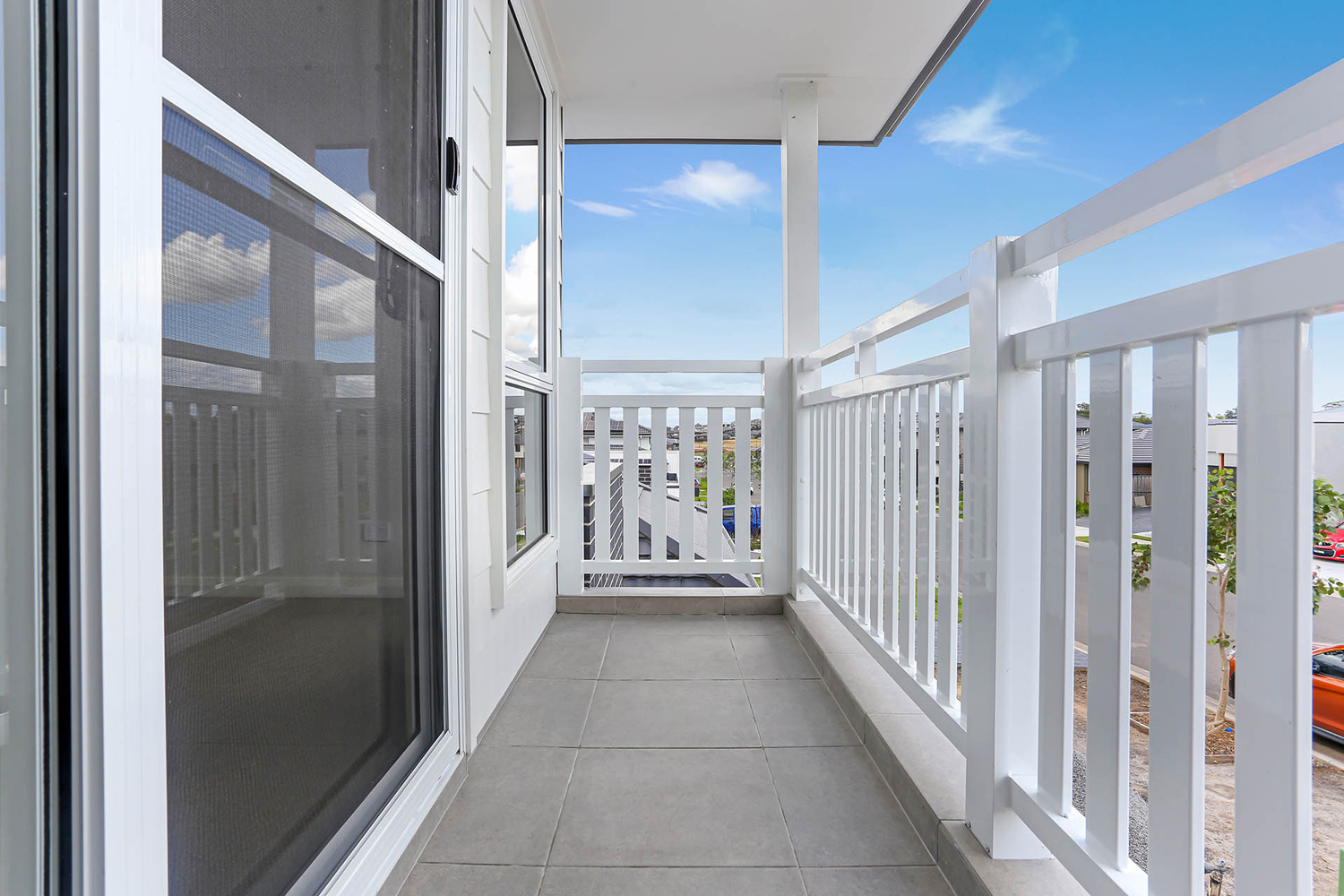 A Balcony With A White Railing And A Blue Sky