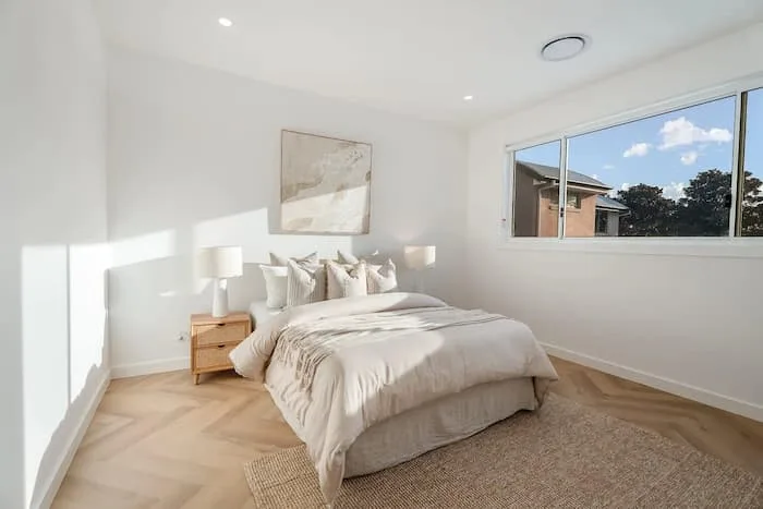Minimalist bedroom with light wood flooring and neutral bedding