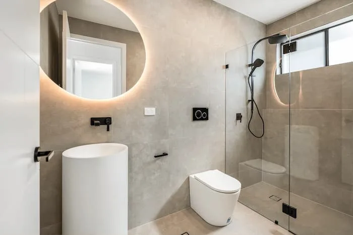 Minimalist bathroom with pedestal sink, glass shower, and soft lighting