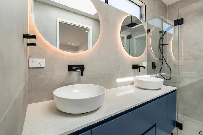 Modern bathroom with double vanity, round mirrors, and glass shower