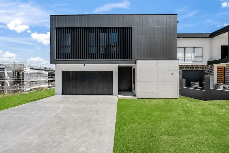 Newly built modern home with driveway, lawn, and active construction