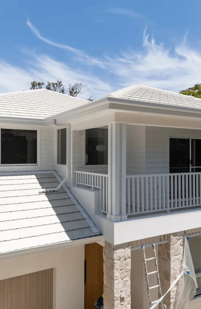 Two-story white house with balcony, stone columns, and garage