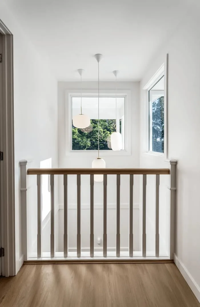 Bright stair landing with pendant lights and white wood railing