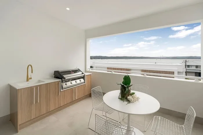 Outdoor patio with grill, wood cabinetry, and coastal view