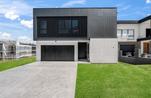 Newly built modern home with driveway, lawn, and active construction