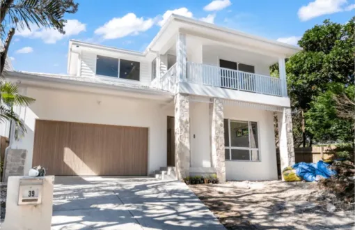 Modern white house with balcony, stone accents, and garage driveway